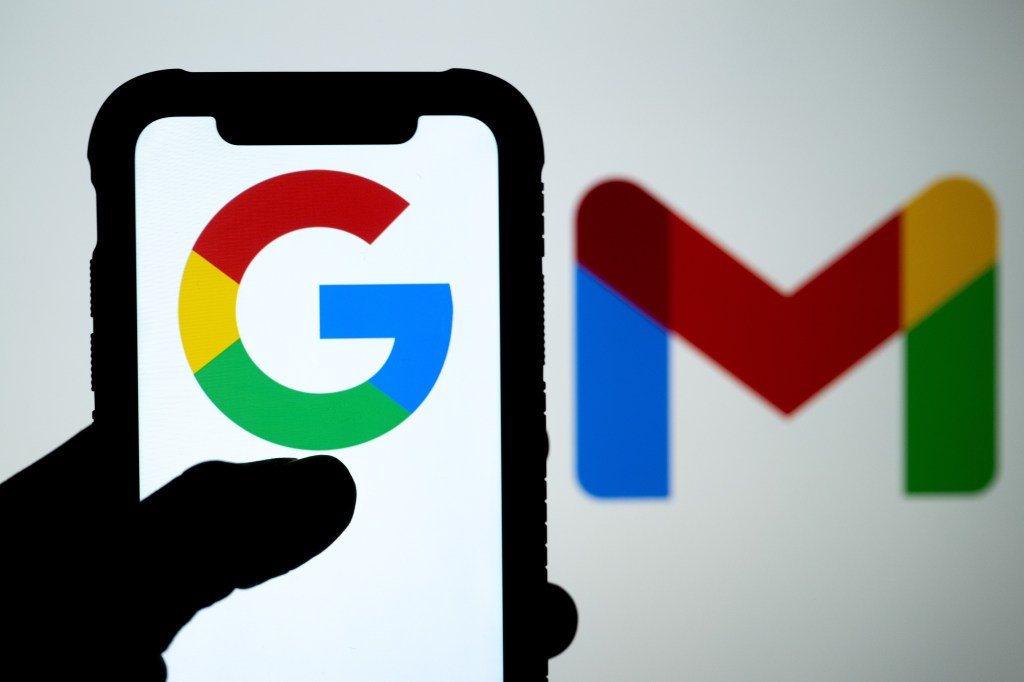 Hand holding a mobile phone displaying Google logo with the Gmail logo in the background, taken in Ankara, Turkiye